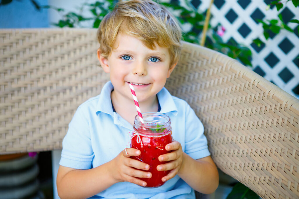 Little Kid boy drinking healthy fruit microgreen smoothie